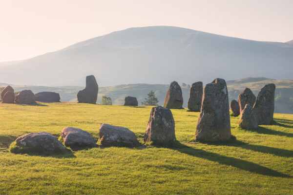 Golden sunrise or sunset light cast across the historic and sacred megalithic site Castlerigg Stone Circle near Keswik, in the Lake District, Cumbria, England.