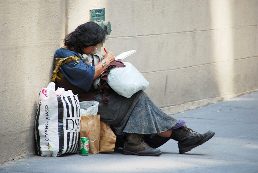 A woman sitting down, writing on a piece of paper, surrounded by shopping bags