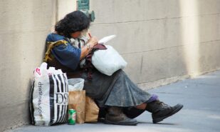 A woman sitting down, writing on a piece of paper, surrounded by shopping bags