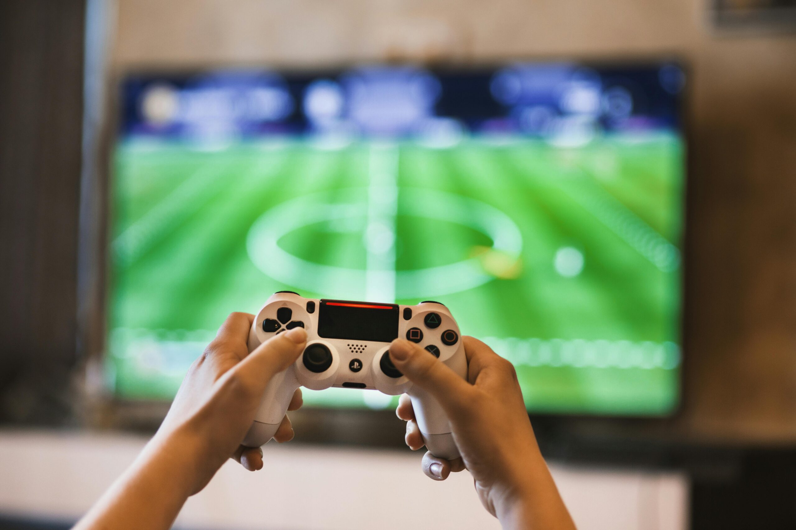 Person Holding Game Pad in front of a screen with a football game on it