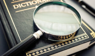 Closeup magnifying glass placed on the dictionary books on the table