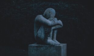 man hugging his knee statue