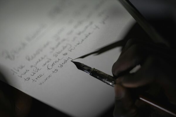 A Person Writing on the Paper Using Fountain Pen