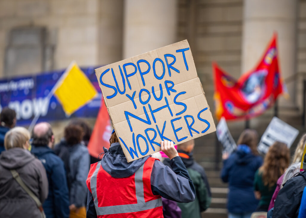 Support your NHS workers at protest rally holding home made placard sign to gain support for NHS key worker staff on march.