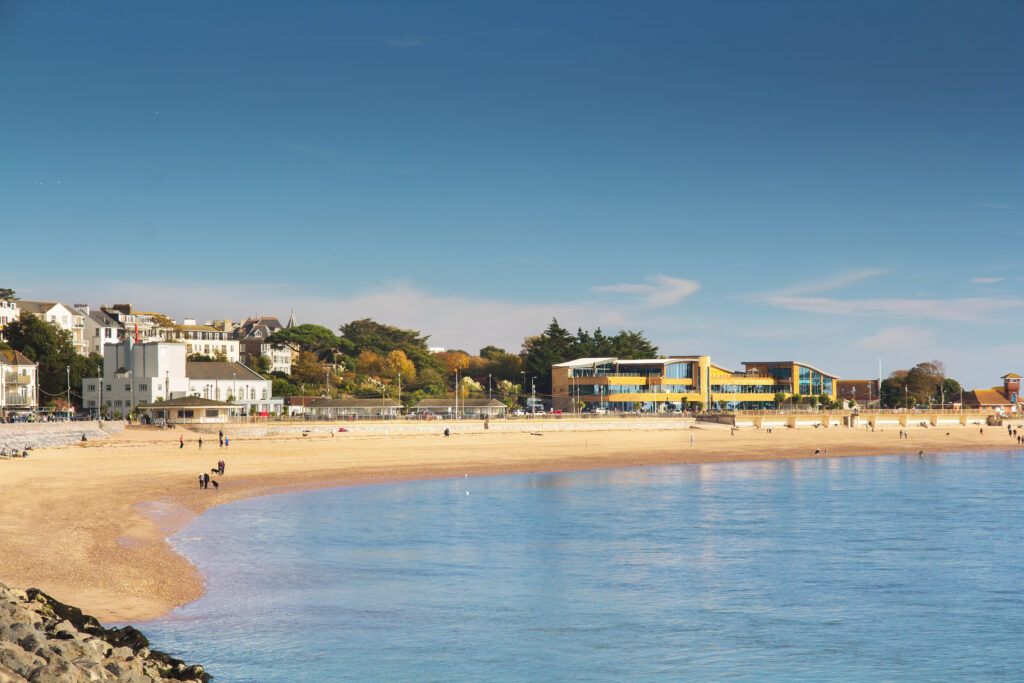View of the coastal city of Exmouth. The city is in the mouth of the river Exe. On a beach in good weather people are walking - tourists and locals