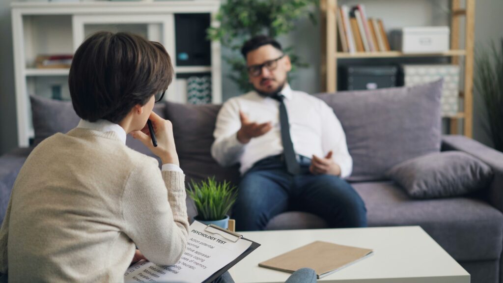 a man and a woman therapist sitting on a couch in a living room