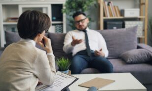 a man and a woman therapist sitting on a couch in a living room