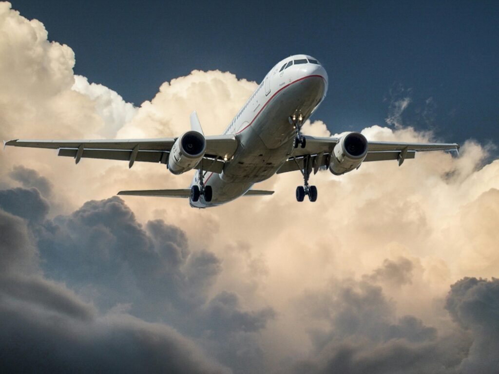 A plane in the sky with clouds behind it