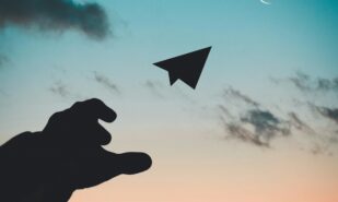 Silhouette of a hand throwing a paper plane