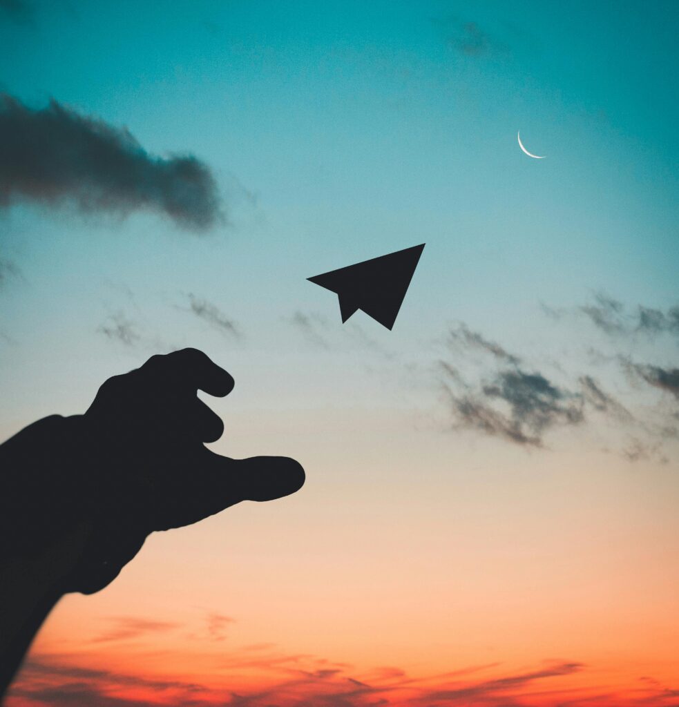 Silhouette of a hand throwing a paper plane