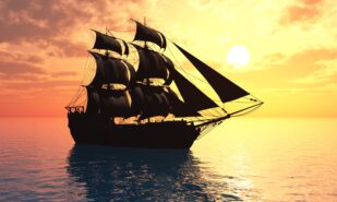 Vintage sailboat in the sea at sunset.