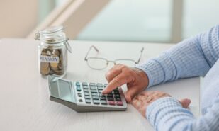 Senior woman counting savings at table. Concept of pension
