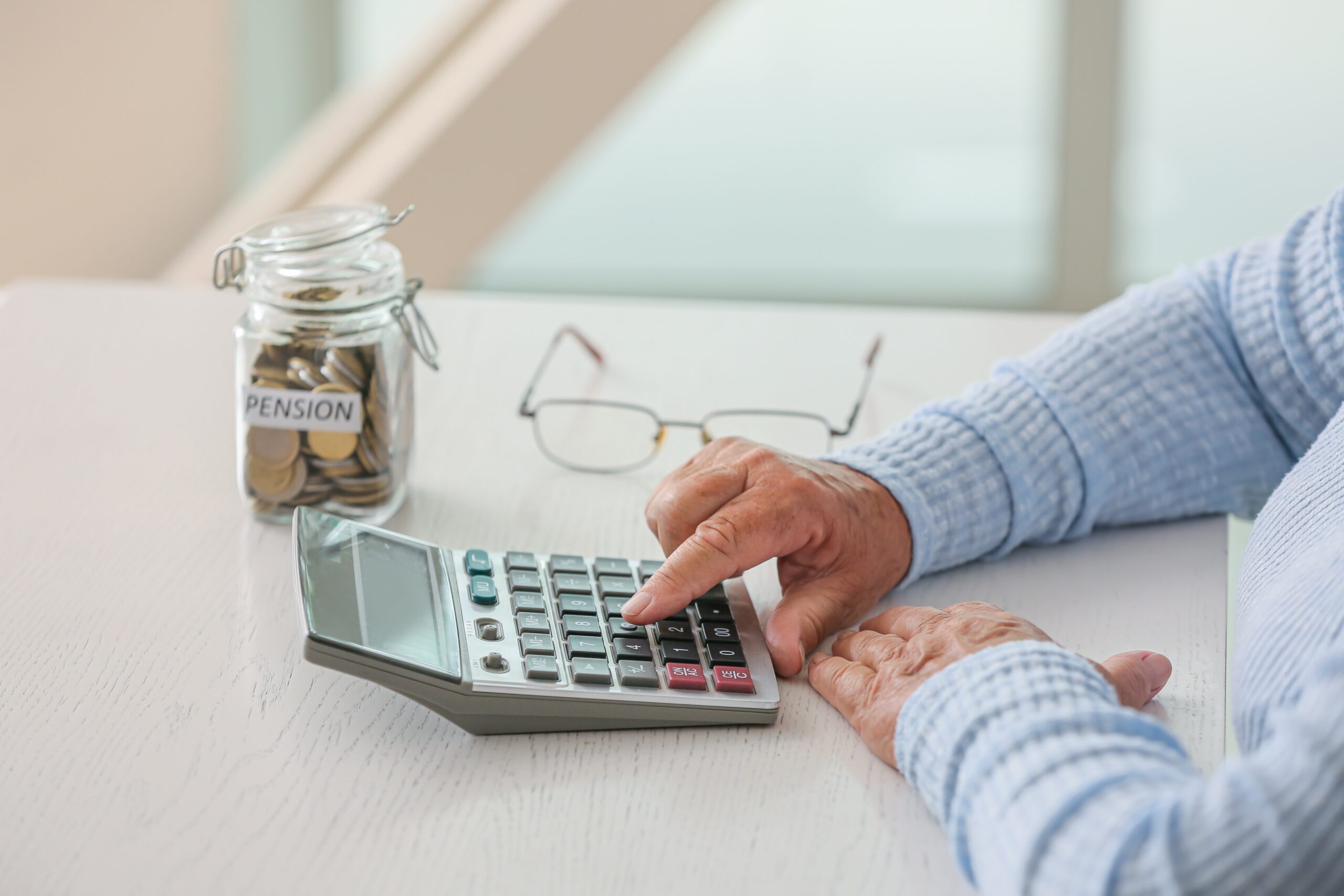 Senior woman counting savings at table. Concept of pension