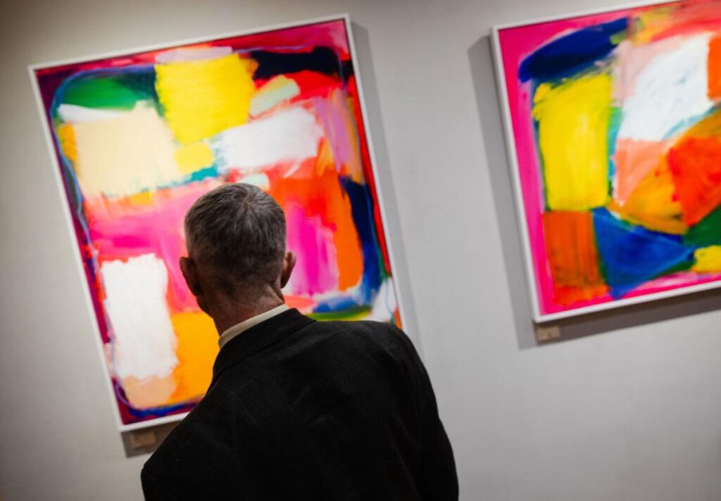 A man looking at Sophie Lévy Burton's paintings. Photo by Marzena Pogorzaly