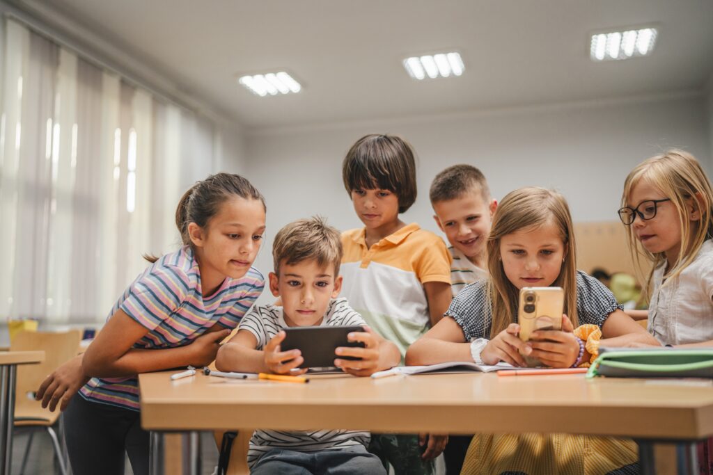 Young students use cellphone for video games on a break in the classroom at school