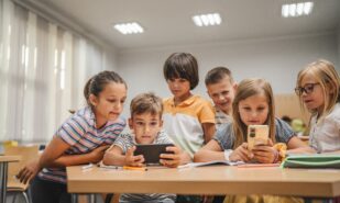 Young students use cellphone for video games on a break in the classroom at school