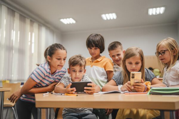 Young students use cellphone for video games on a break in the classroom at school