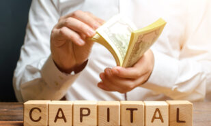 Businessman counts money on the background of the caption Capital. Capitalism, capital increase and influence. Financial liberalization of developing countries, unprincipled withdrawal of capital.