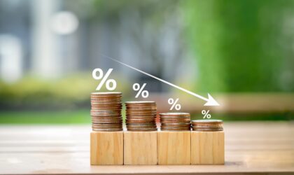 Low interest rates. Percentage sign on different high of coins stack and arrow going down. Business and financial banking, reducing interest rates payment, mortgage rate, loan and tax concept.