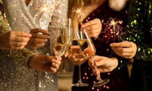 Beautiful women with champagne and Christmas sparklers at Christmas party, closeup