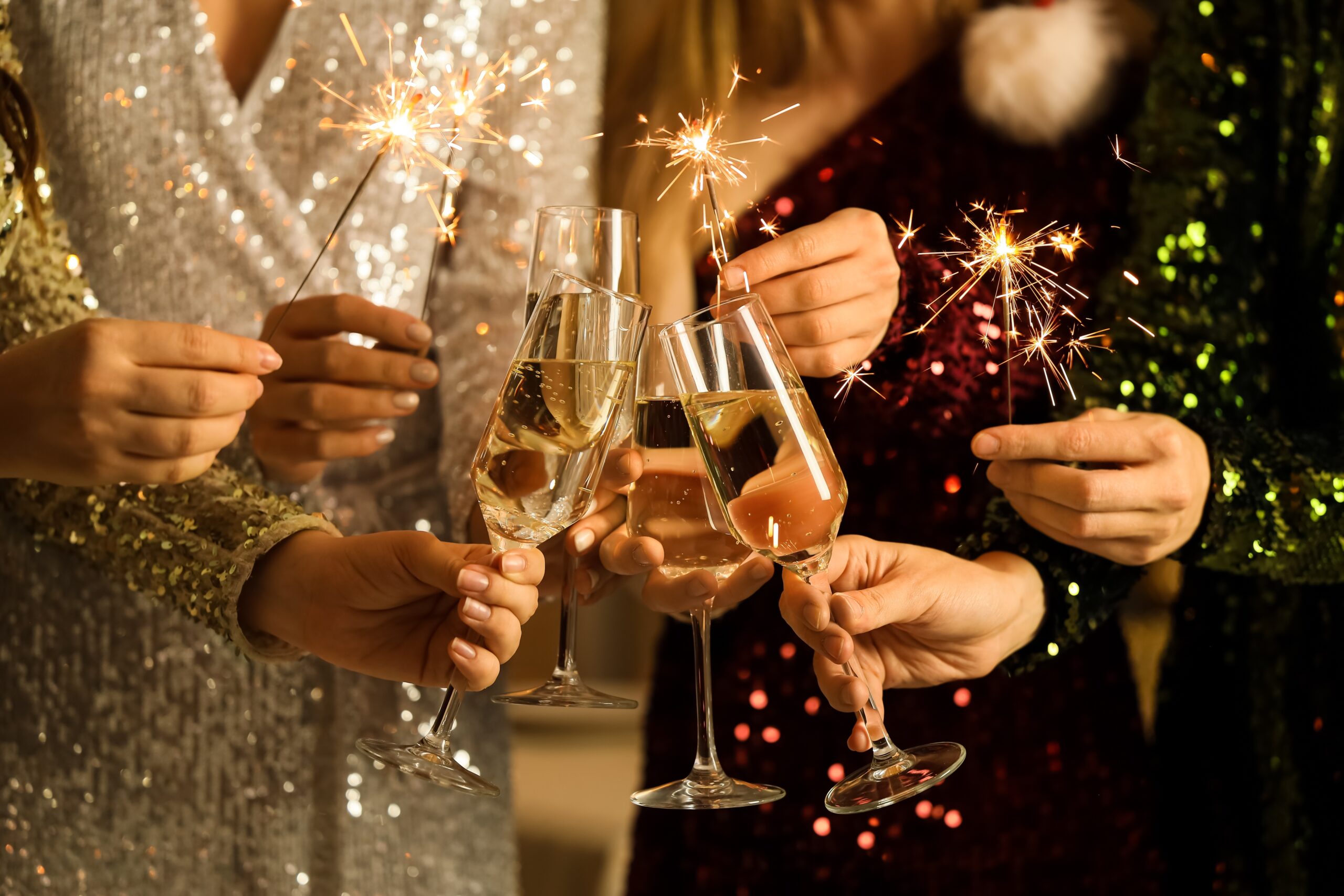 Beautiful women with champagne and Christmas sparklers at Christmas party, closeup