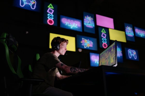 Young man playing computer games against a background of screens