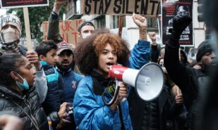 woman in blue jacket protesting with megaphone