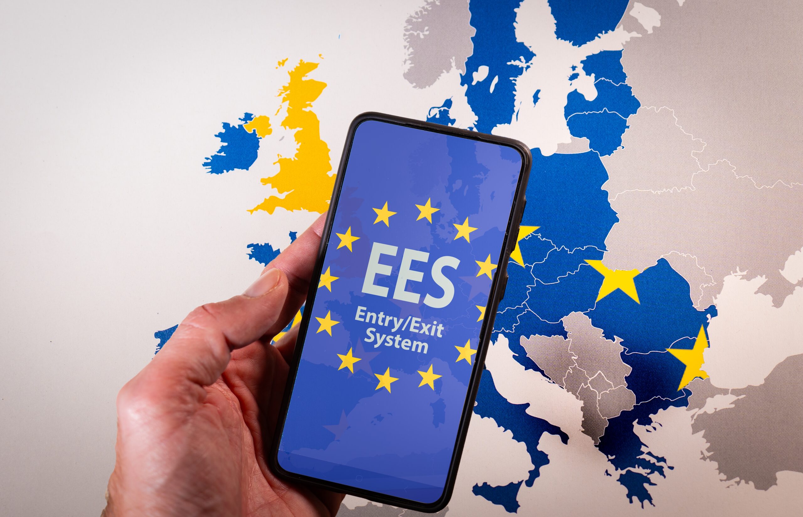 Hand holding a smartphone displaying the European Union EES EntryExit System on screen, symbolizing border control, travel regulation, and digital security within the Schengen Area