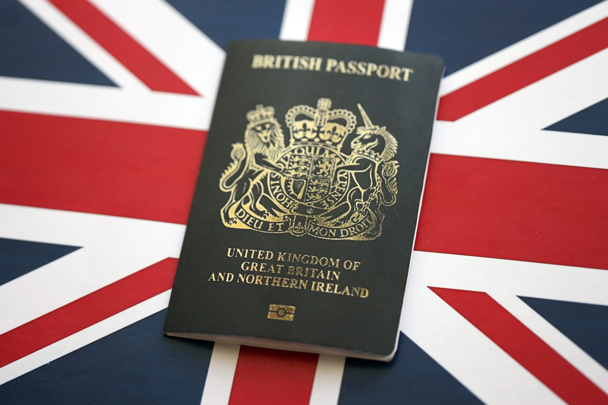 Black British passport on UK Union Jack flag close up
